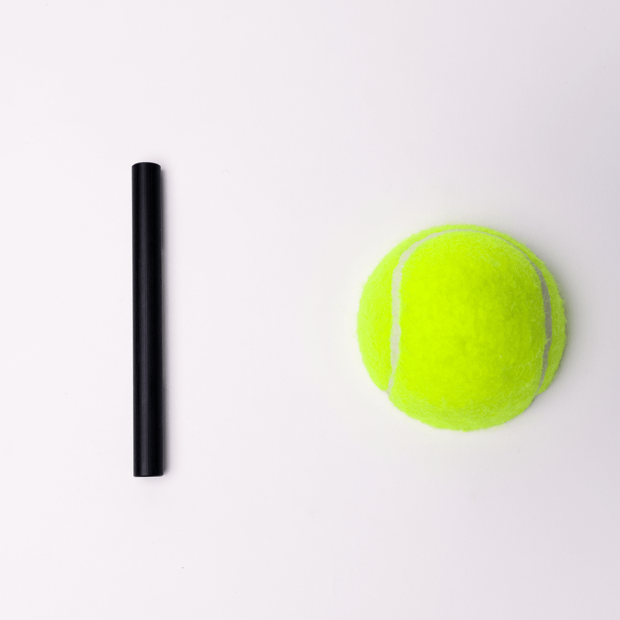 Black rod beside a bright yellow tennis ball on a light background, showcasing size comparison and colors.