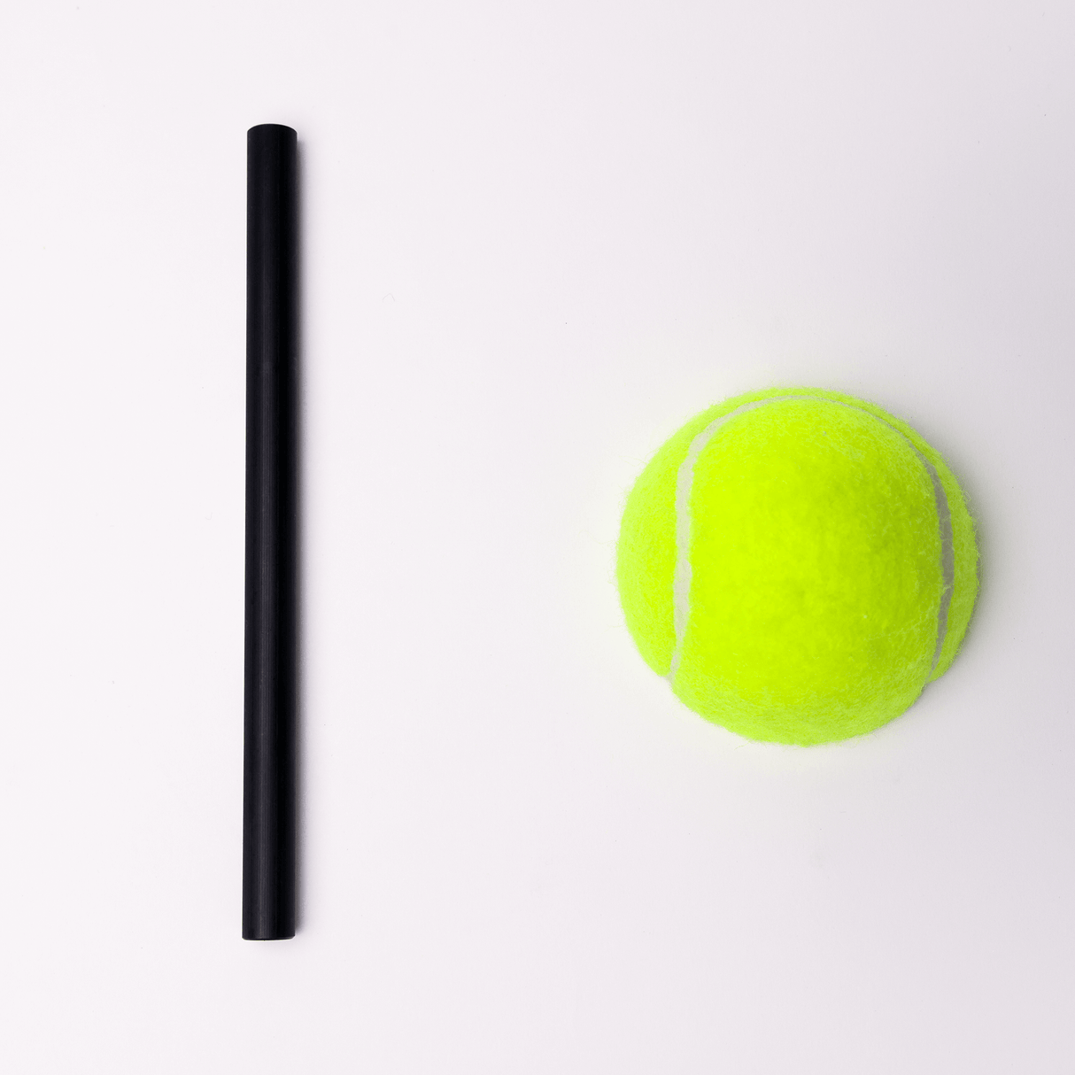Black rod next to a bright green tennis ball on a white background, highlighting distinct shapes and colors.