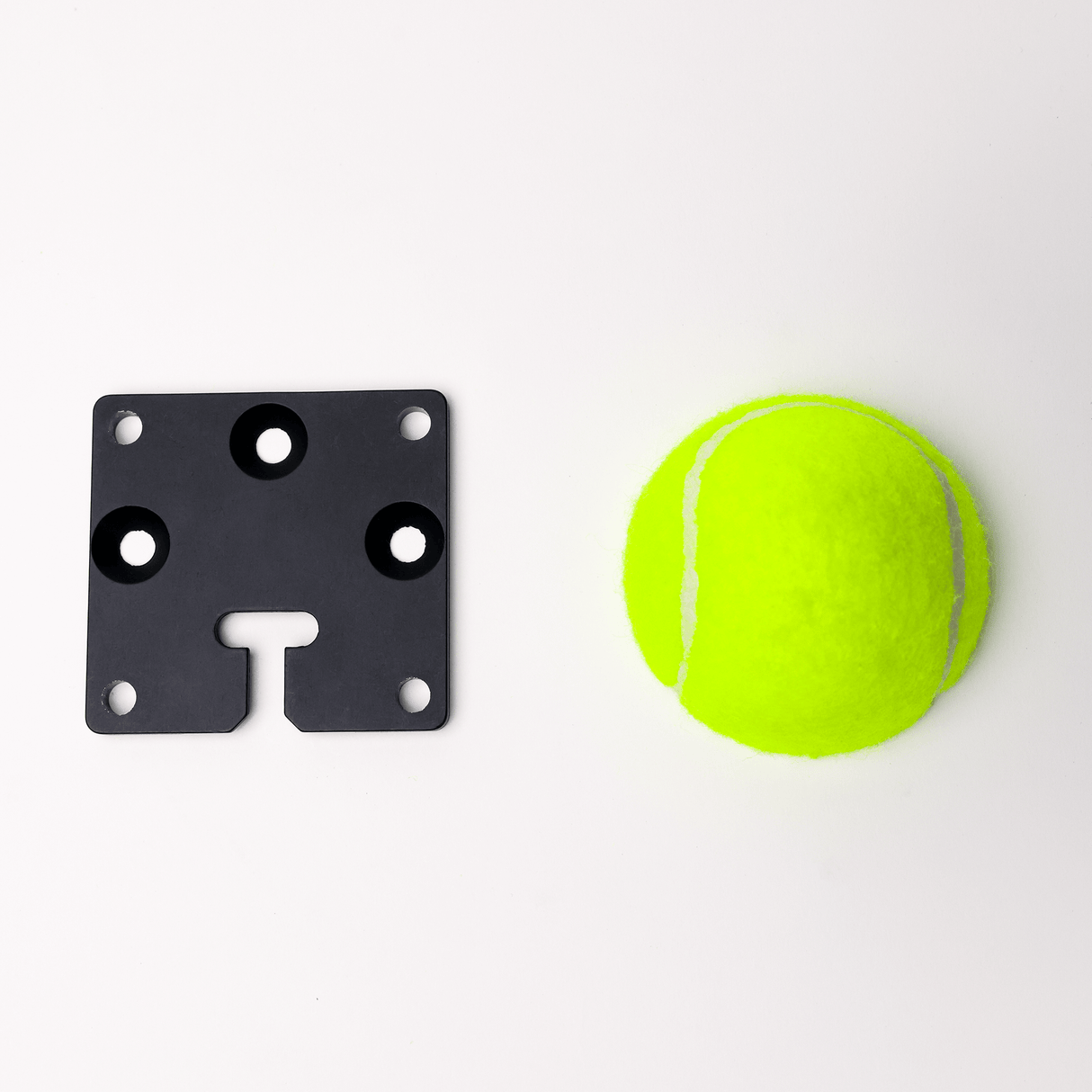 MicroGrip rigging plate beside a bright yellow tennis ball, showcasing versatile mounting solutions.