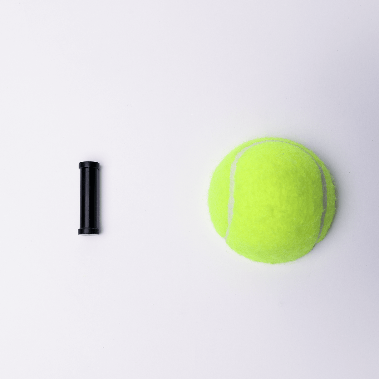 Black tubing next to a bright green tennis ball on a white background.