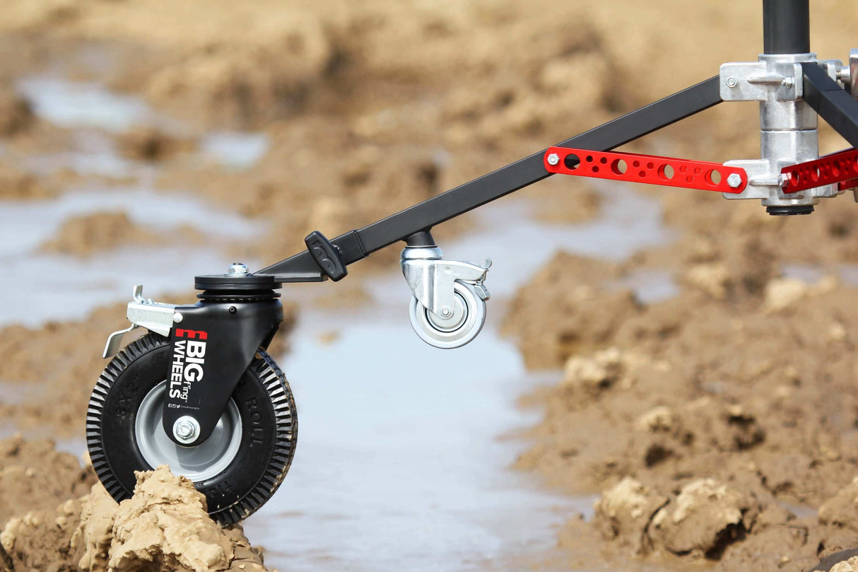 Close-up of Big F’ing™ wheel attached to a monitor stand, showcasing its durable, foam semi-pneumatic tire on rough terrain.