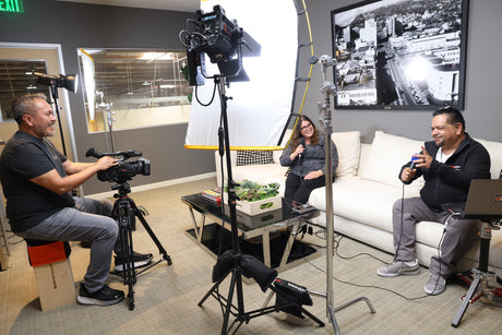 Content creators filming an interview setup with multiple lights and cameras in a modern studio.